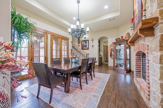 dining space with a notable chandelier, dark wood-type flooring, a raised ceiling, and a healthy amount of sunlight