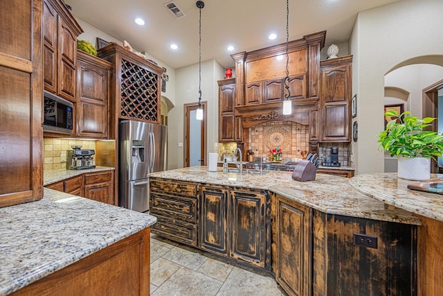 kitchen featuring black microwave, backsplash, hanging light fixtures, stainless steel fridge with ice dispenser, and light stone countertops