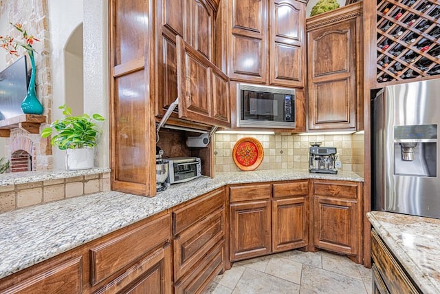 kitchen featuring tasteful backsplash, light stone counters, stainless steel fridge with ice dispenser, and black microwave