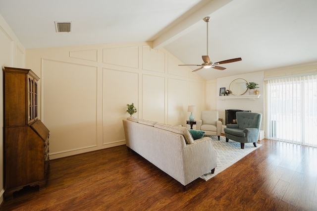 living room with dark hardwood / wood-style floors, ceiling fan, a fireplace, and lofted ceiling with beams