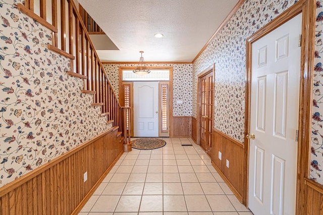 tiled foyer entrance with a textured ceiling and ornamental molding