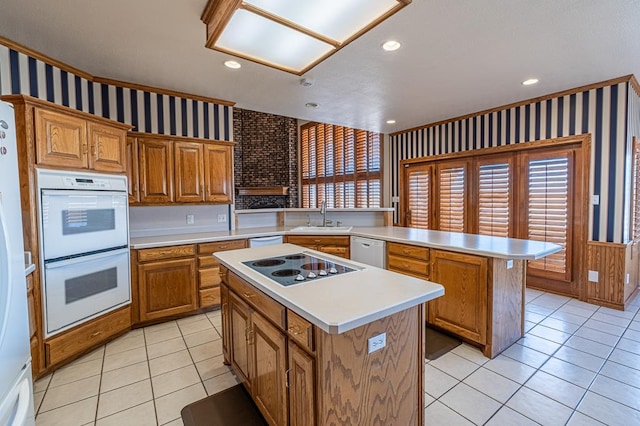 kitchen with sink, white appliances, light tile patterned floors, and a center island