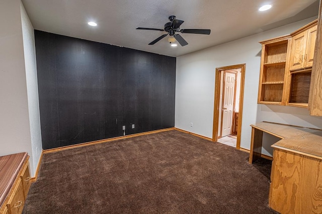 carpeted spare room featuring ceiling fan and built in desk