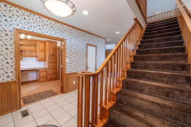 stairs featuring crown molding, wood walls, tile patterned floors, and built in desk