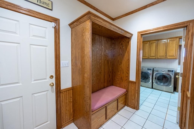 mudroom with light tile patterned floors, crown molding, washing machine and dryer, and wooden walls