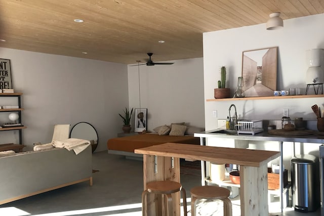 kitchen featuring ceiling fan, wooden ceiling, and concrete floors