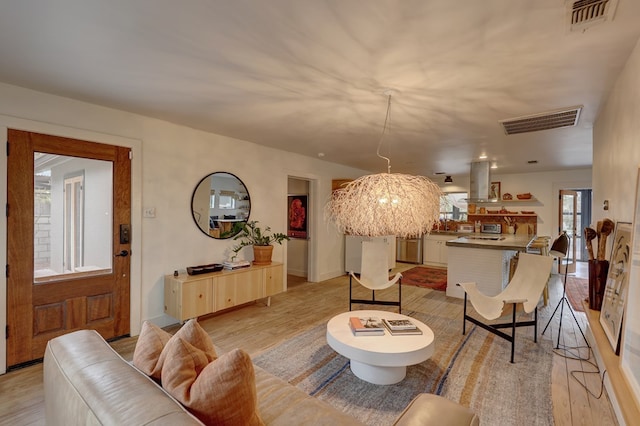 living room with light wood-type flooring and an inviting chandelier