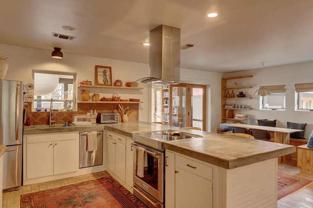 kitchen featuring sink, island exhaust hood, light hardwood / wood-style floors, kitchen peninsula, and stainless steel appliances