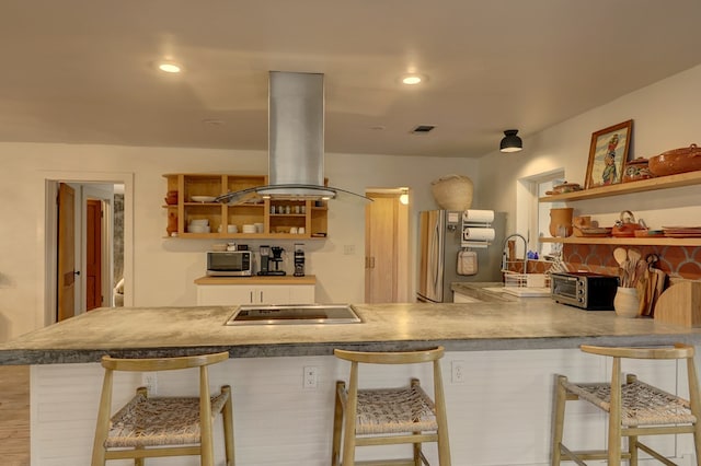 kitchen with a breakfast bar, kitchen peninsula, and island exhaust hood