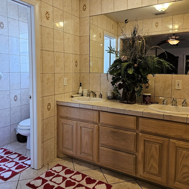 bathroom featuring tile patterned flooring, a sink, and tile walls