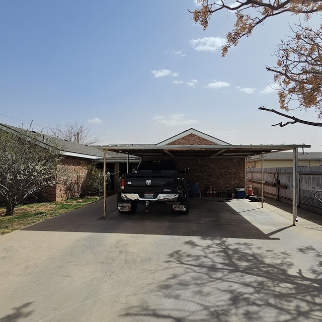 view of car parking with a carport, driveway, and fence