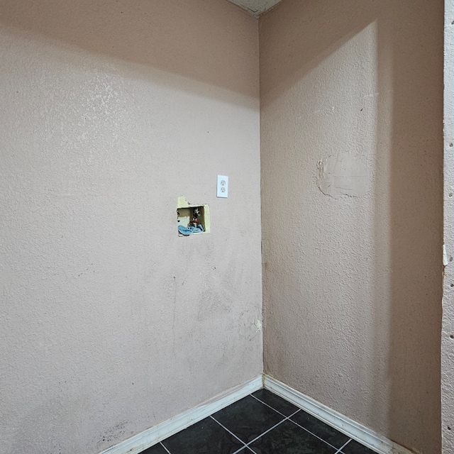 clothes washing area featuring hookup for a washing machine, dark tile patterned flooring, laundry area, and baseboards