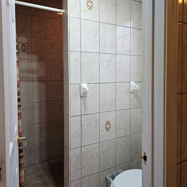 full bath featuring tiled shower and toilet