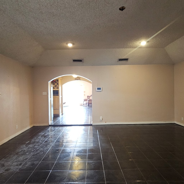 unfurnished room with arched walkways, tile patterned floors, visible vents, and baseboards