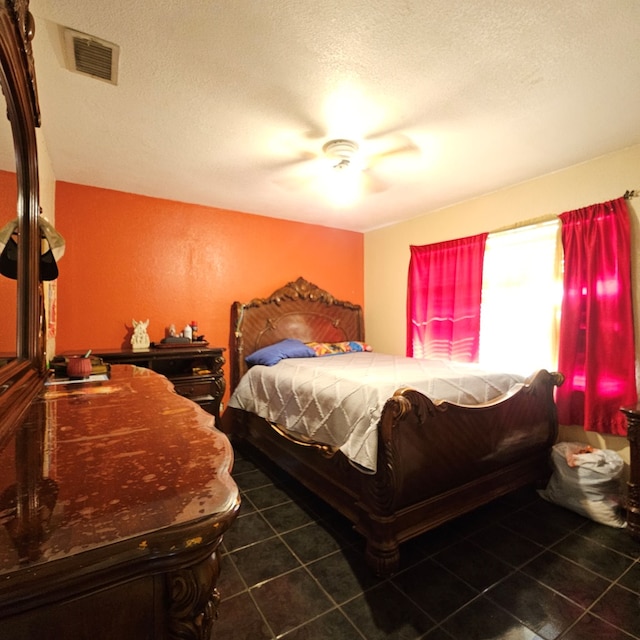 bedroom featuring a textured ceiling, tile patterned flooring, visible vents, and a ceiling fan