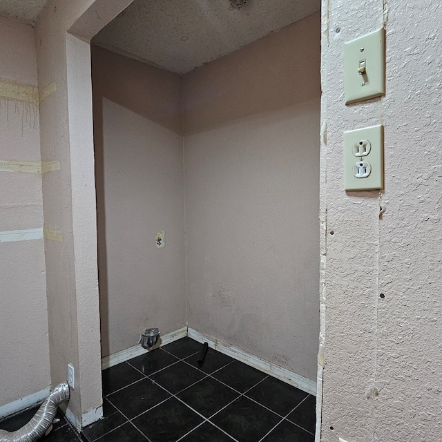 clothes washing area featuring dark tile patterned flooring, electric dryer hookup, and baseboards