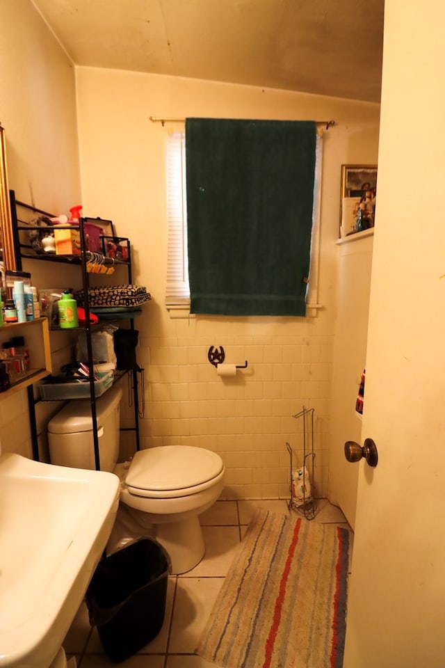 bathroom featuring toilet, tile patterned floors, tile walls, and sink