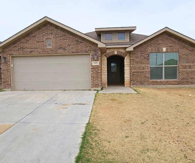 view of front of house featuring concrete driveway, a garage, brick siding, and roof with shingles