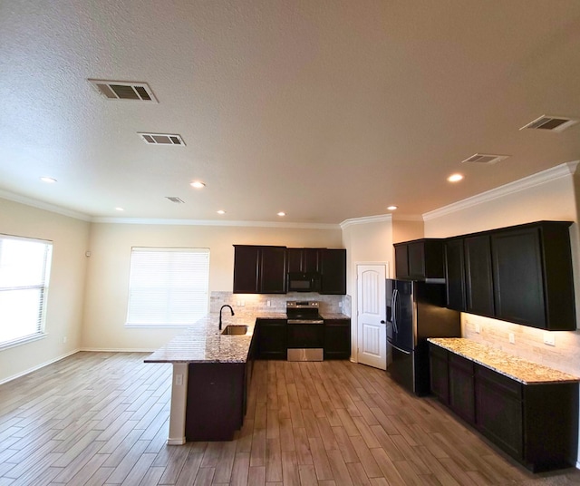 kitchen featuring black appliances, a peninsula, decorative backsplash, and visible vents