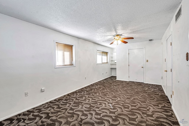 unfurnished bedroom featuring ceiling fan, a textured ceiling, and dark colored carpet