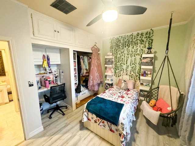 bedroom with light wood-type flooring, a closet, ceiling fan, and crown molding