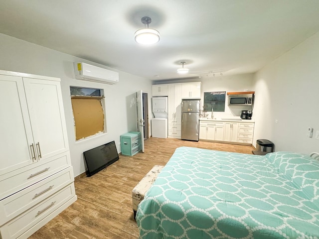 bedroom with a wall mounted air conditioner, stainless steel fridge, and light wood-type flooring