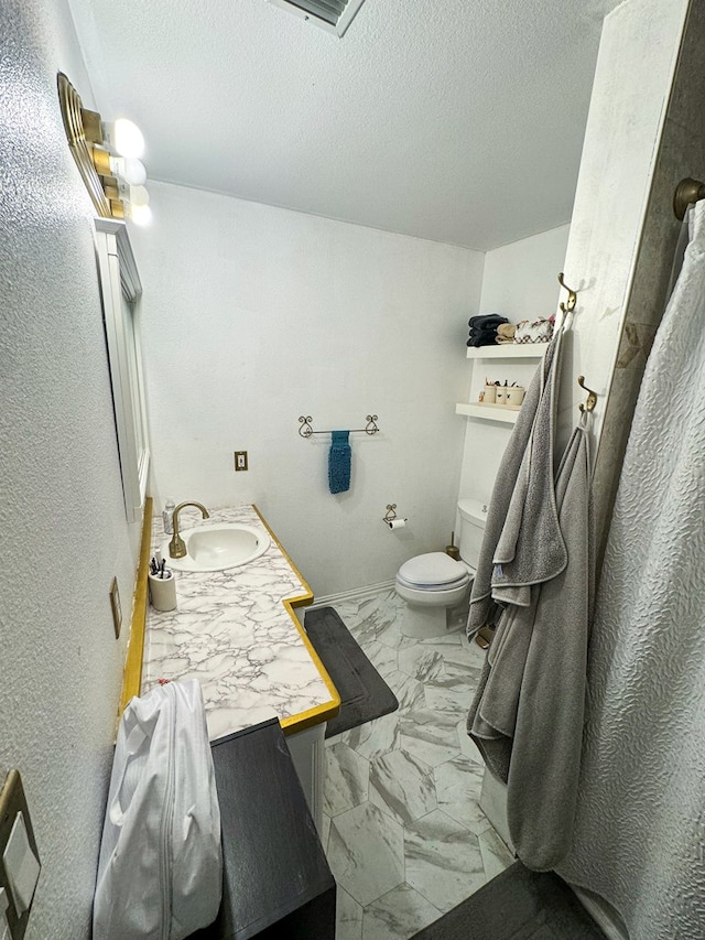 bathroom with a textured ceiling, vanity, and toilet