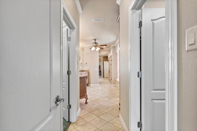 hallway with light tile patterned floors and crown molding