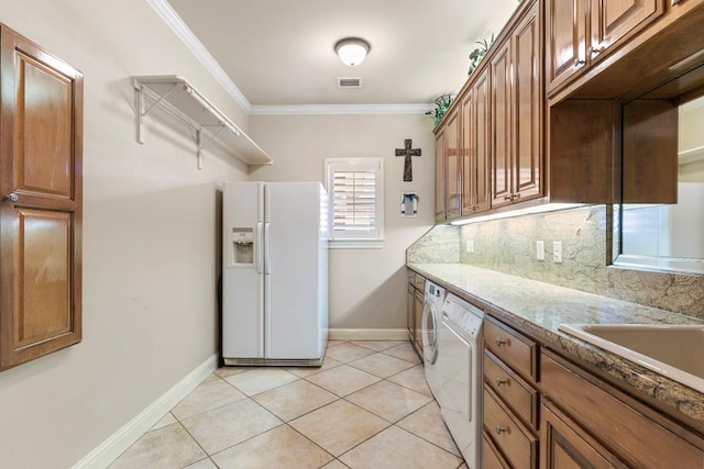 kitchen with stone counters, washing machine and dryer, ornamental molding, light tile patterned floors, and white fridge with ice dispenser