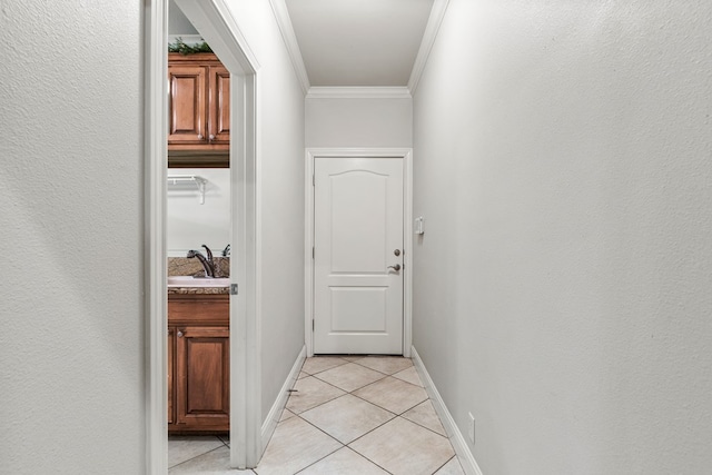 corridor with light tile patterned floors, sink, and ornamental molding