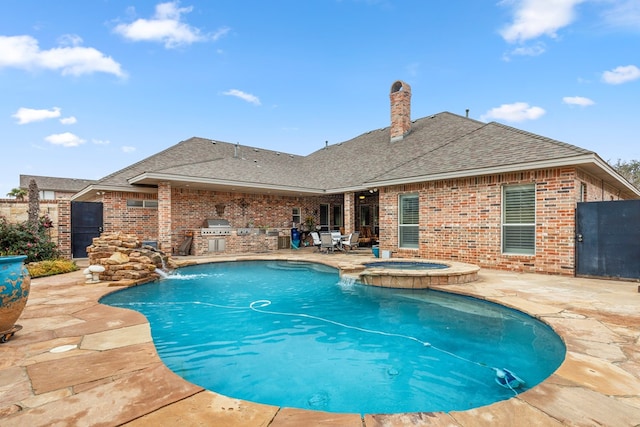 view of pool with exterior kitchen, pool water feature, an in ground hot tub, a patio, and area for grilling