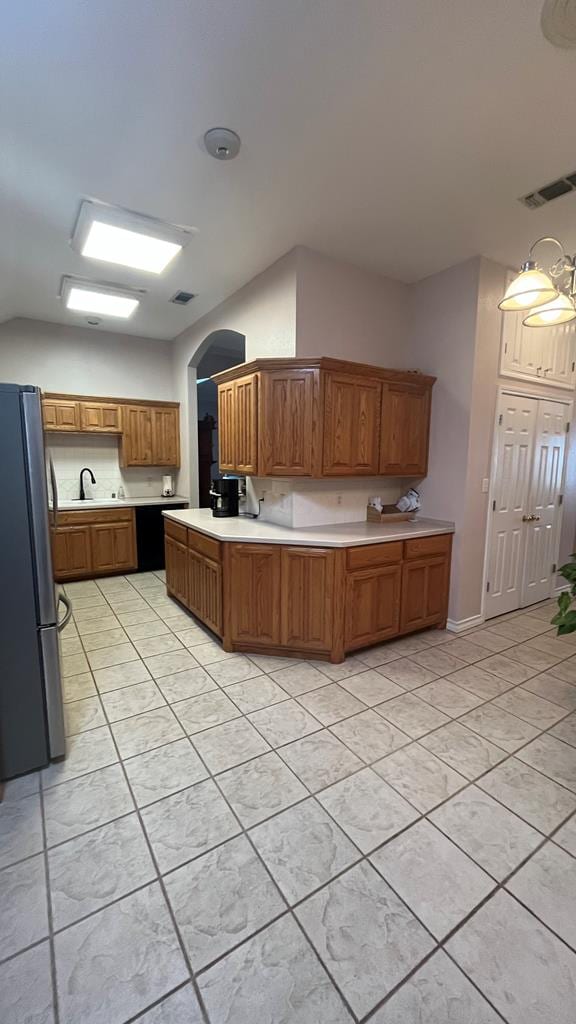 kitchen featuring stainless steel fridge, decorative light fixtures, and kitchen peninsula