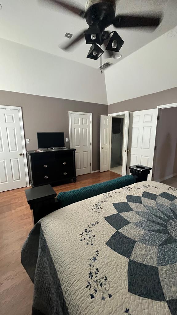 bedroom with ceiling fan, high vaulted ceiling, and wood-type flooring