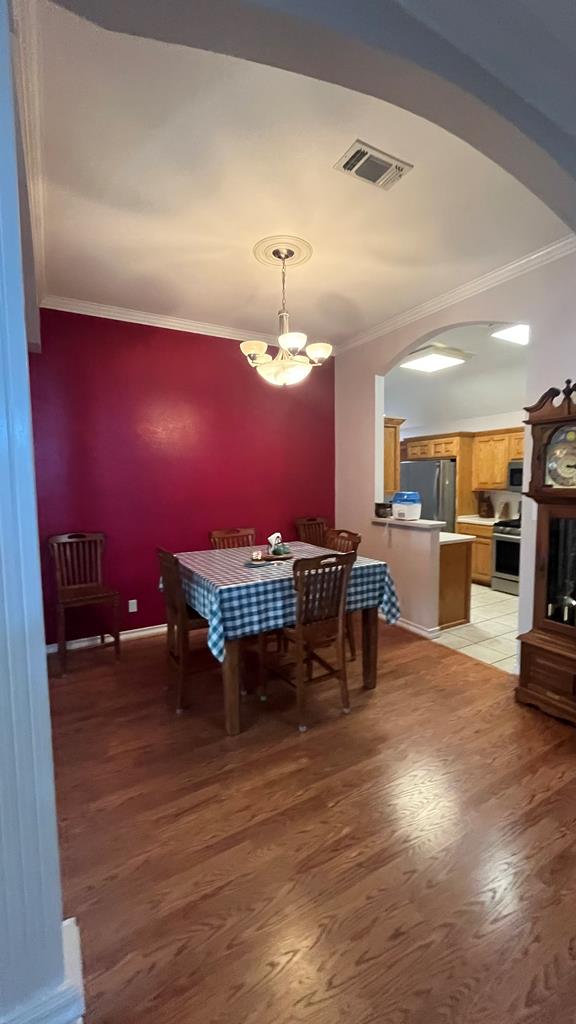 dining room with crown molding, hardwood / wood-style flooring, and a notable chandelier