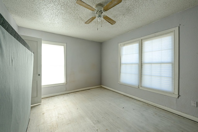 unfurnished room featuring ceiling fan, light hardwood / wood-style floors, and a textured ceiling