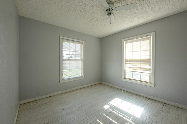 spare room featuring ceiling fan, a healthy amount of sunlight, and light hardwood / wood-style flooring