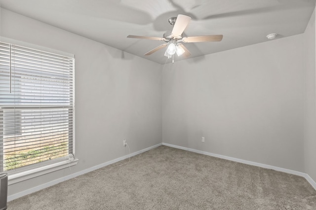 empty room with light carpet, a ceiling fan, and baseboards