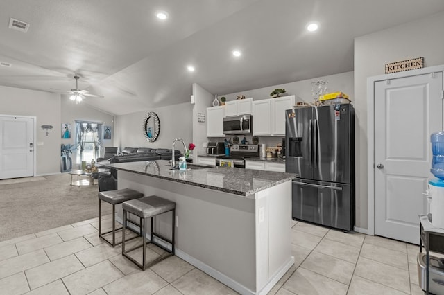 kitchen with lofted ceiling, a sink, visible vents, white cabinets, and appliances with stainless steel finishes