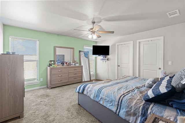 carpeted bedroom with a ceiling fan, visible vents, and baseboards