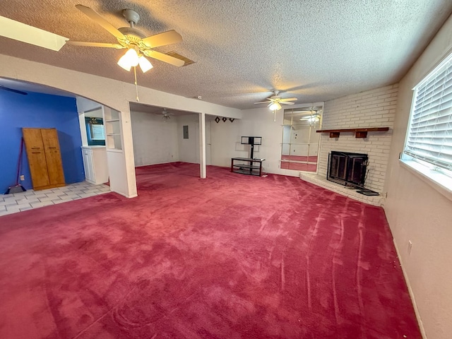 basement featuring ceiling fan, light colored carpet, a textured ceiling, and a brick fireplace