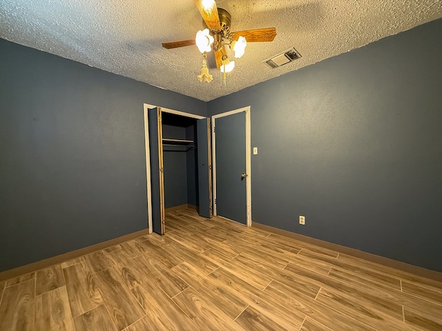 unfurnished bedroom featuring ceiling fan, a closet, light hardwood / wood-style floors, and a textured ceiling