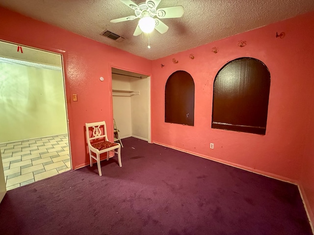 unfurnished bedroom featuring carpet flooring, a textured ceiling, a closet, and ceiling fan