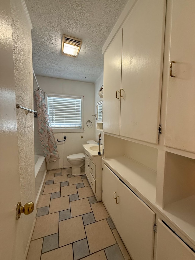 full bathroom with shower / tub combo, tile patterned floors, a textured ceiling, vanity, and toilet