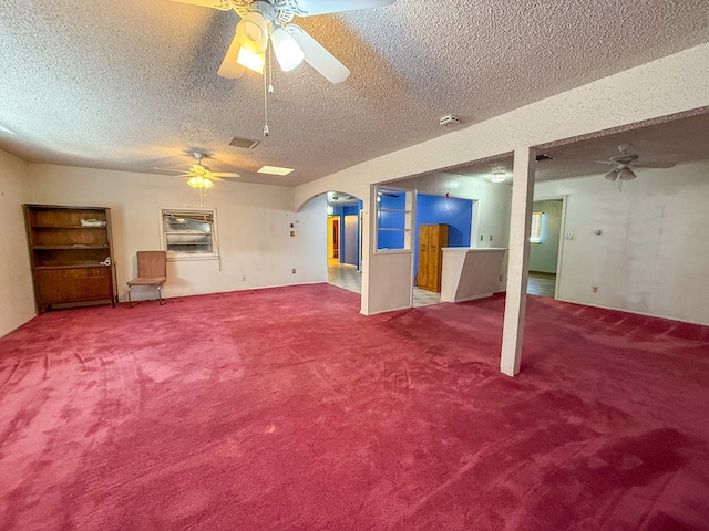 basement with ceiling fan, carpet floors, and a textured ceiling