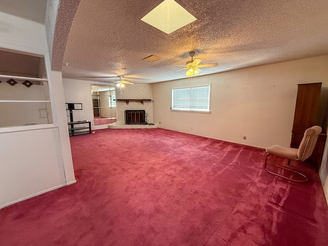 unfurnished living room with ceiling fan, carpet, a textured ceiling, and a brick fireplace