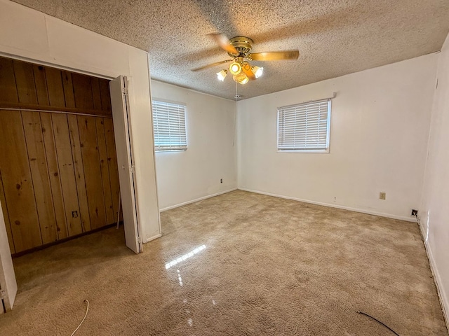 unfurnished bedroom featuring light carpet, a textured ceiling, a closet, and ceiling fan