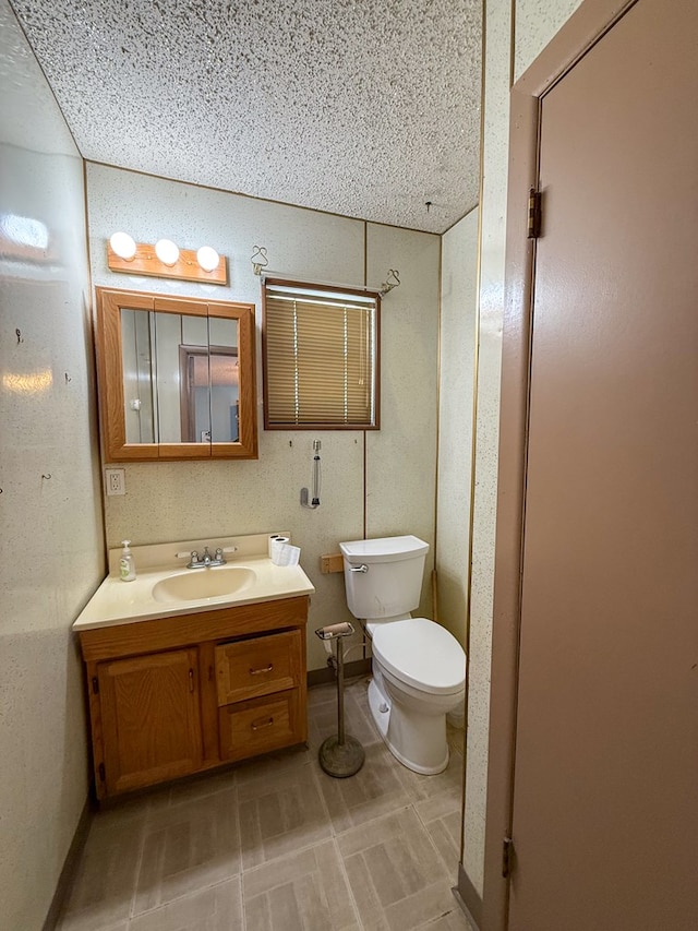 bathroom featuring vanity, toilet, and a textured ceiling