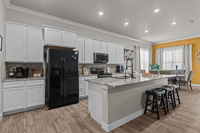 kitchen featuring crown molding, tasteful backsplash, white cabinets, an island with sink, and black appliances