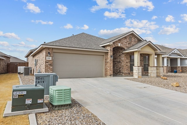 view of front of home with brick siding, a shingled roof, concrete driveway, central AC, and a garage