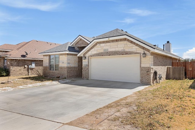 french country home with brick siding, a chimney, concrete driveway, an attached garage, and fence